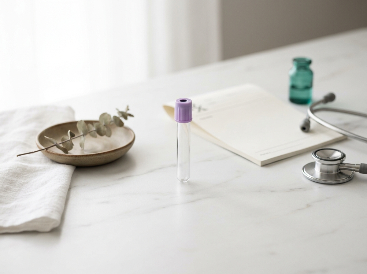 Tube de prélèvement sanguin avec bouchon coloré, ordonnance papier vierge et stéthoscope posés sur un plan en marbre clair